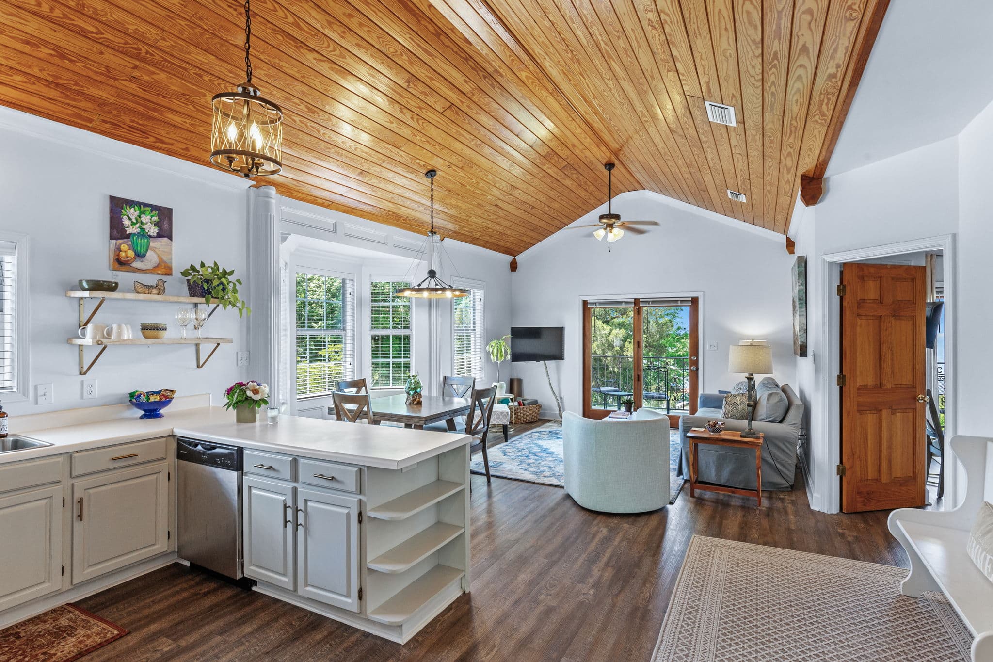 Main view of living area and full kitchen with hardwood vaulted ceiling