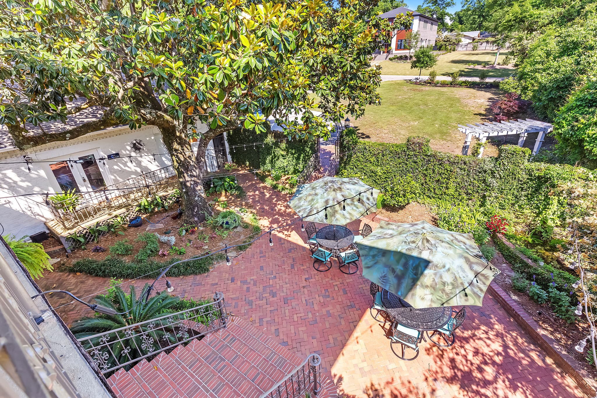 Bird's eye view of brick paved courtyard with patio umbrellas, chairs, and tables