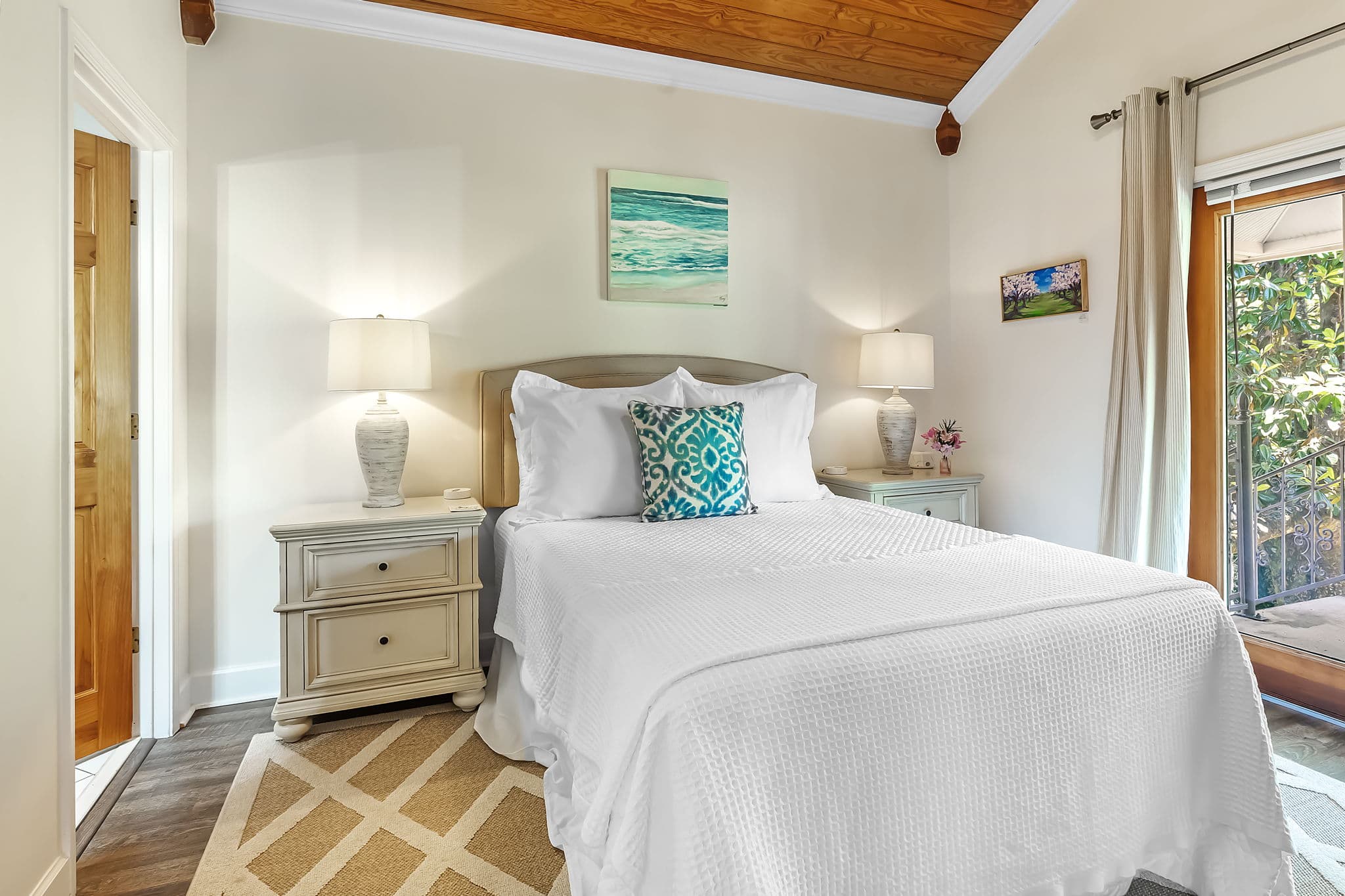 Second Bedroom with king bed topped with immaculate white bedding, wooden nightstand with table lamp
