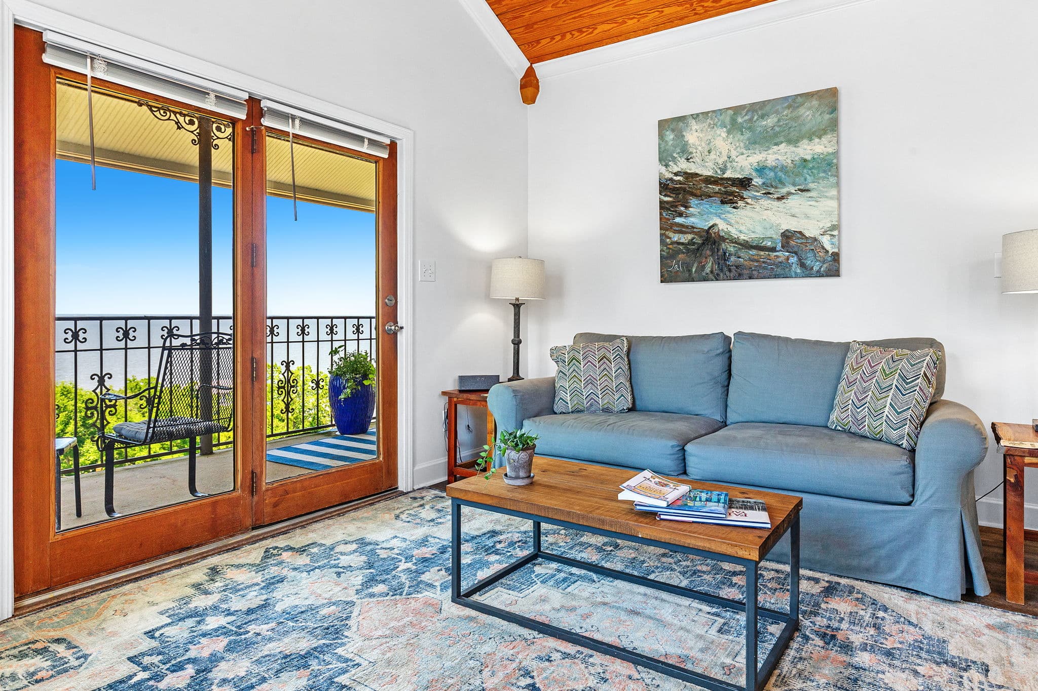 Sitting Area with blue loveseat, coffee table, and sliding doors leading to balcony with bay view
