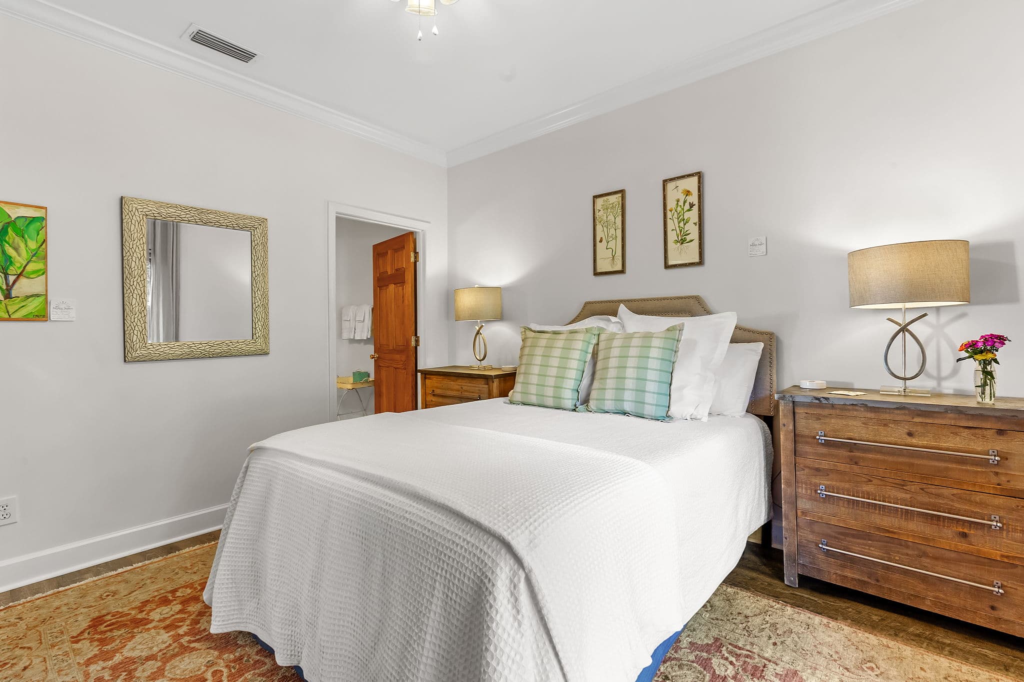Second Bedroom in tranquil neutral tones with king bed, wooden bedside bureaus, and door leading to attached bathroom