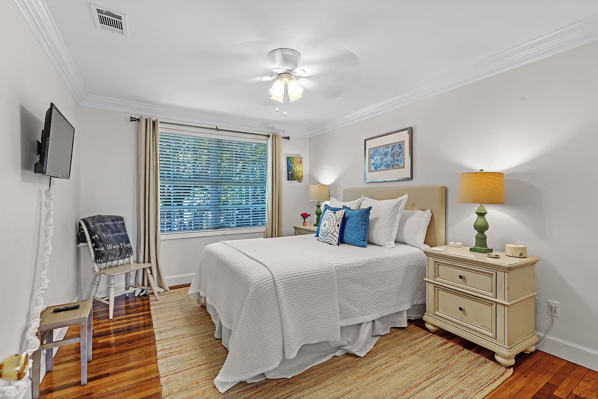 Second Bedroom with queen bed, matching bedside tables with table lamps, a wall-mounted flat-screen TV, and a wide window for plenty of natural light