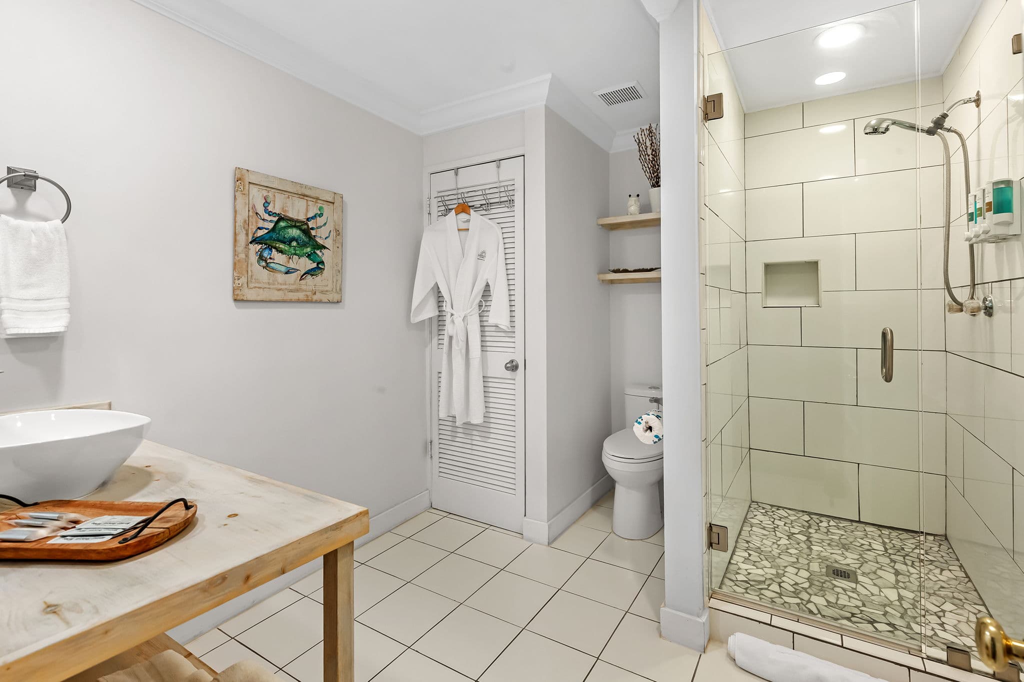 Spacious bathroom with wooden vanity, vessel sink, walk-in tiled shower, and toilet