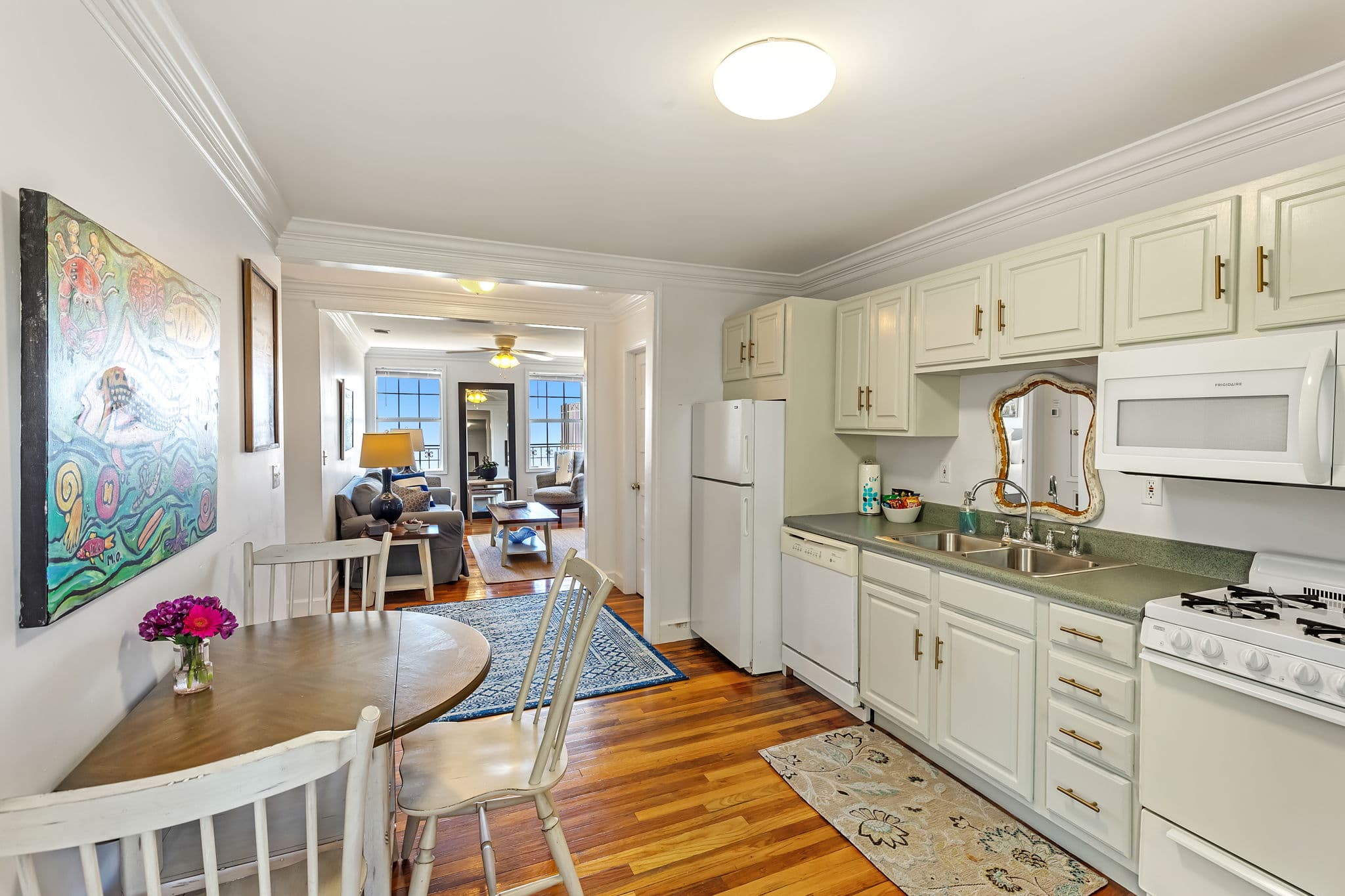 Fully equipped, eat-in kitchen with hardwood floor, refrigerator, sink, stove, microwave, and cabinetry