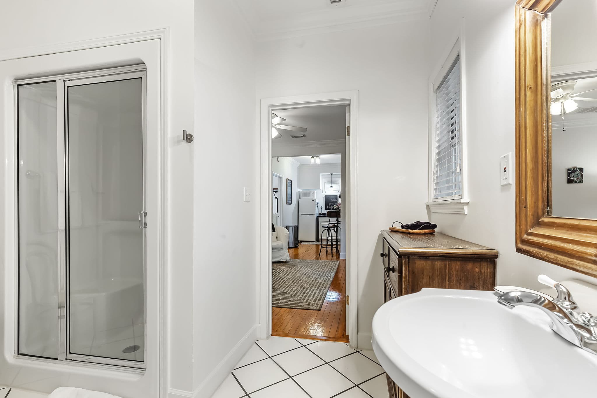 Attached private bathroom with shower, a sink with a mirror, and tiled floors.
