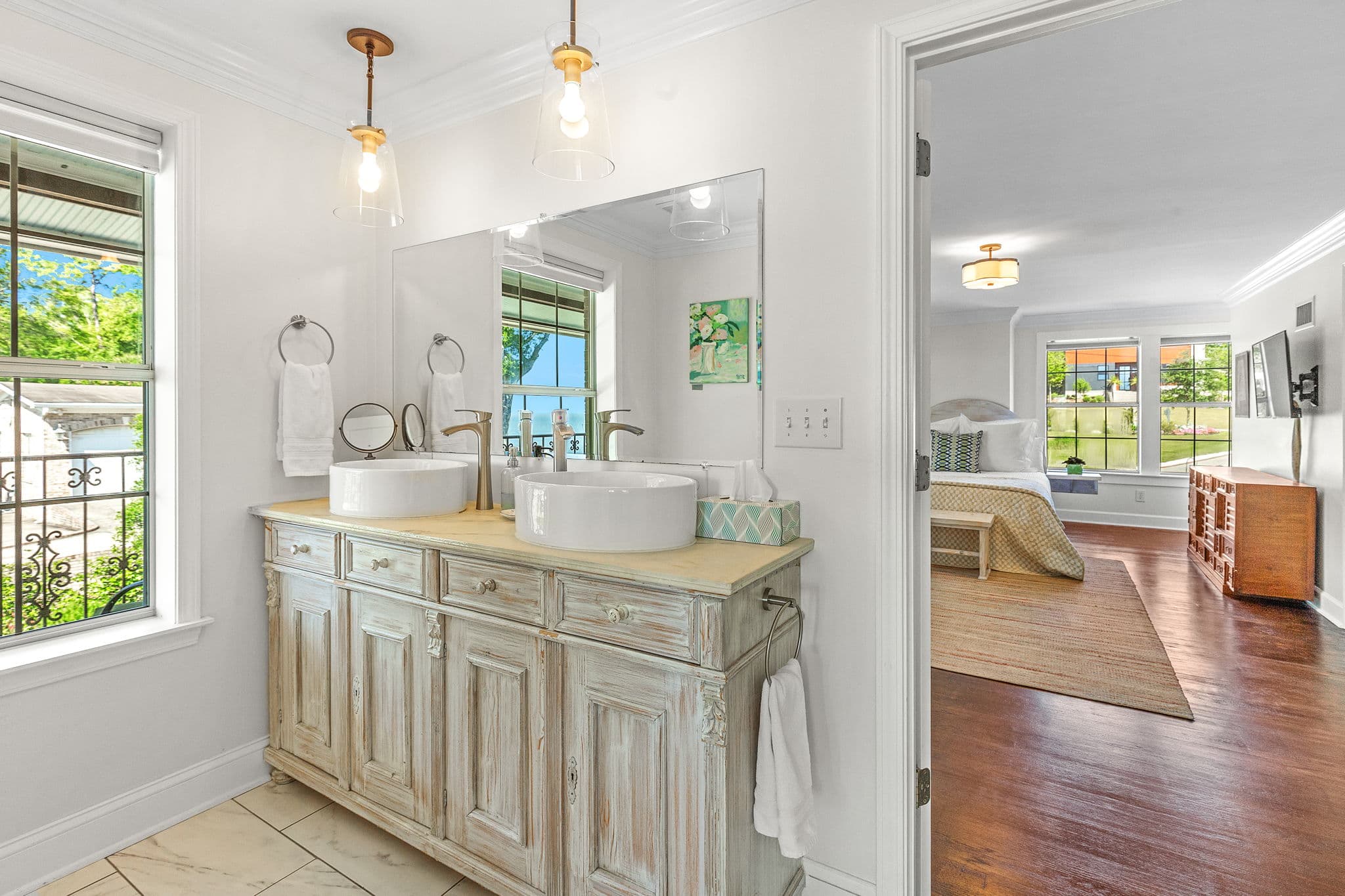 Private bathroom between rooms with double sink vanity and window with bay views