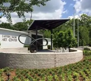 A modern art center entrance featuring a distinctive sculpture and landscaped surroundings.