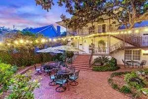 A charming garden patio with outdoor seating and string lights, set against a picturesque home at twilight.