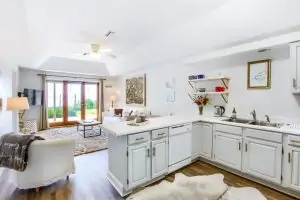 Bright, modern kitchen open to a comfortable living area with natural light and outdoor access.