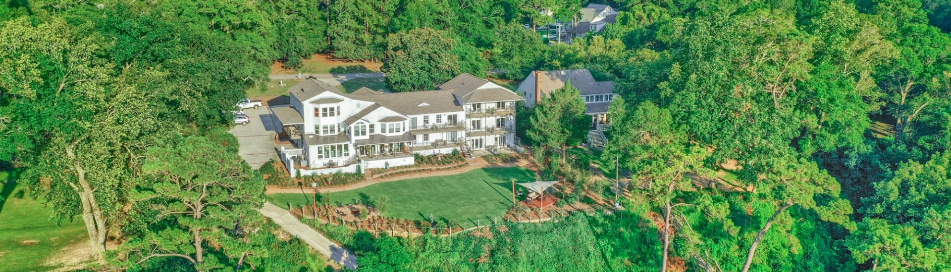 Aerial view of a large, modern home surrounded by lush greenery.