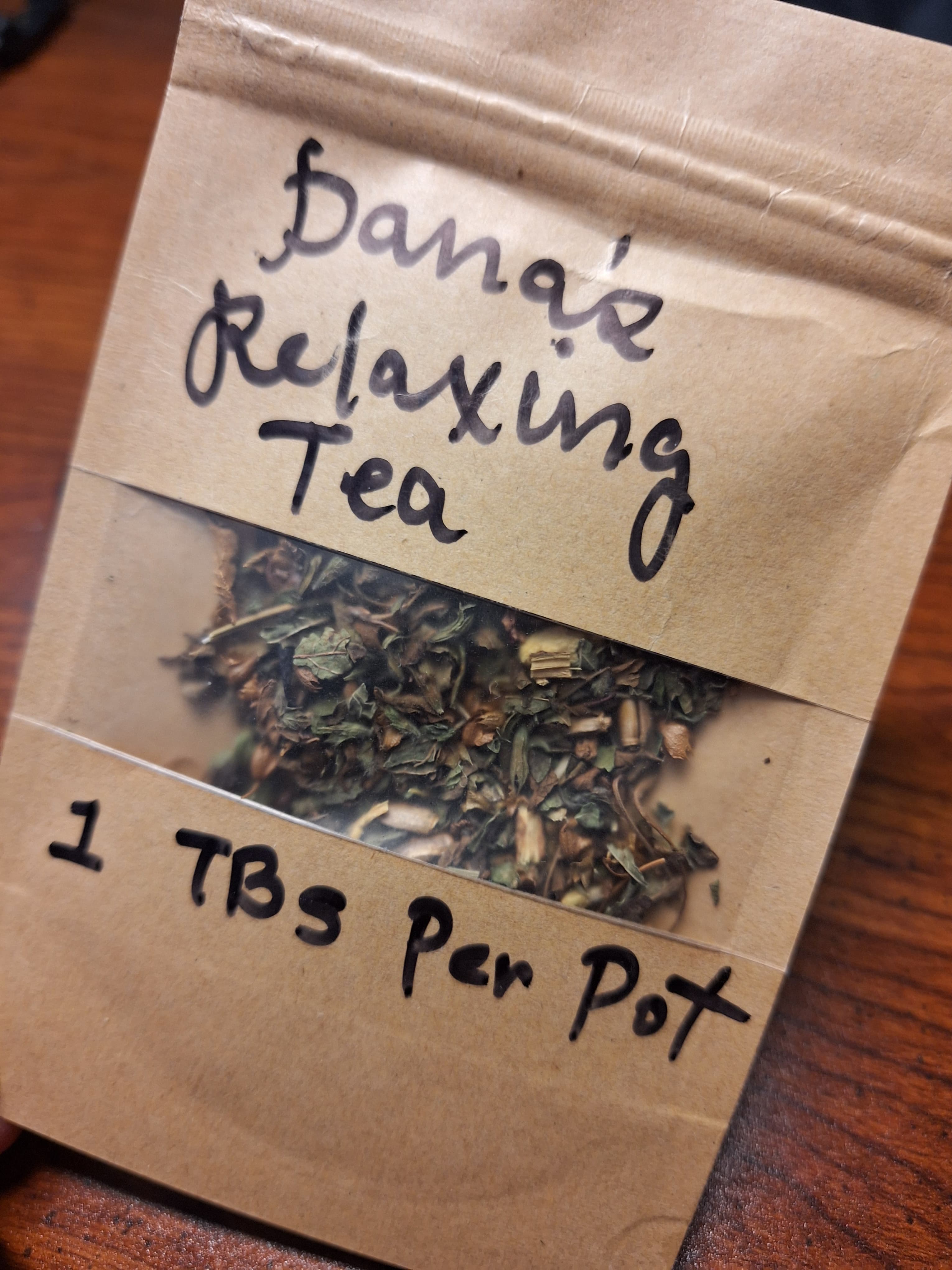 A brown bag with tea leaves inside, with the tea named Dana's Relaxing Tea