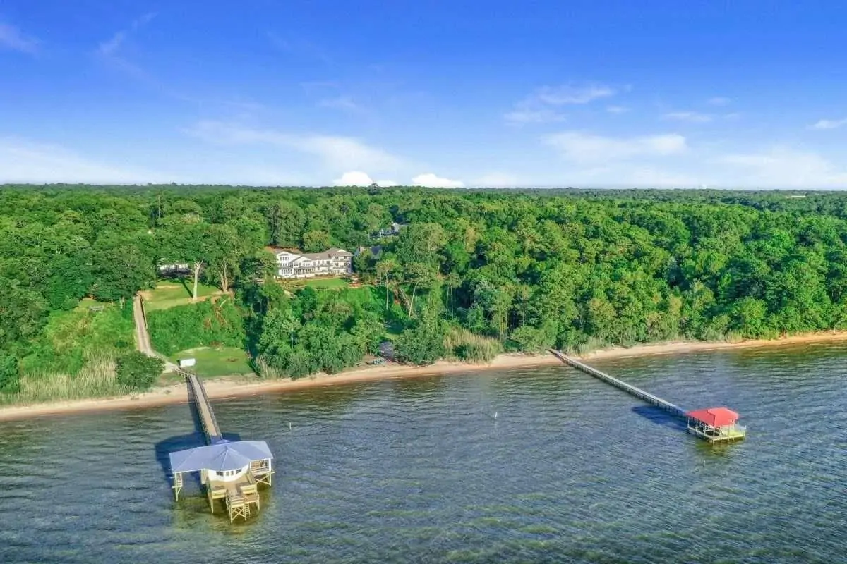 Aerial view of a shoreline with docks, surrounded by lush greenery and a clear blue sky. Aerial view of a shoreline with docks, surrounded by lush greenery and a clear blue sky.