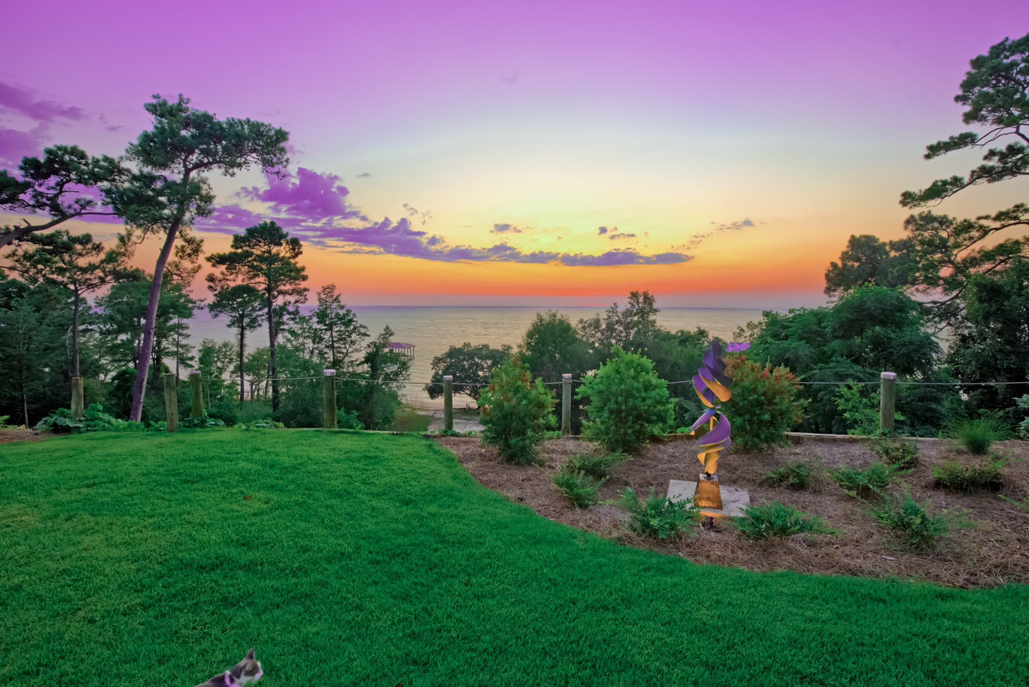 Sunset of purples, oranges, and yellows over the Bluff with the bay waters beyond