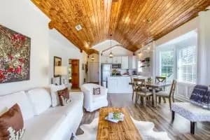 Bright, modern living space with wooden beams, a white sofa, and dining area.
