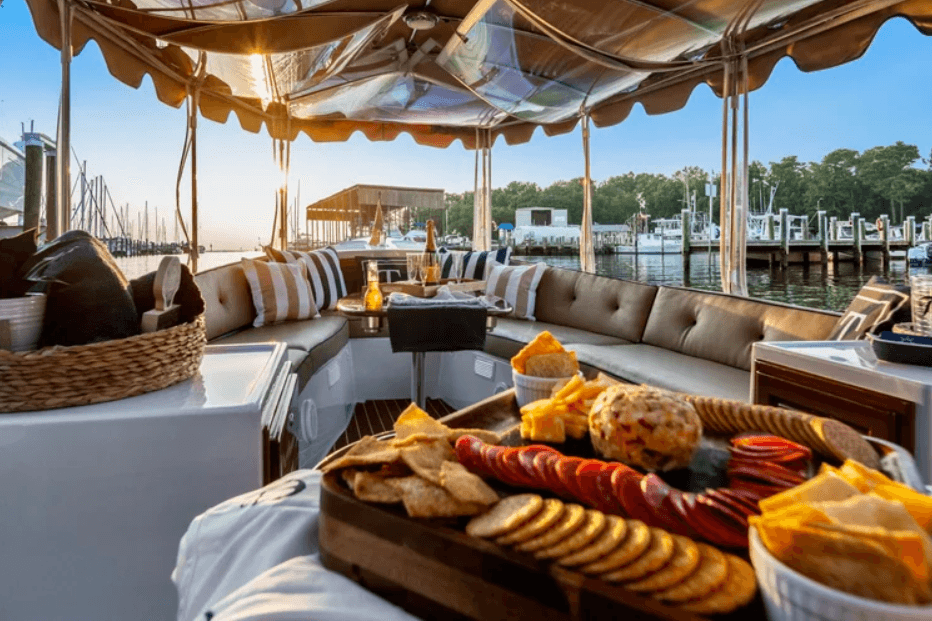 A stylish boat deck featuring a gourmet snack spread and a scenic waterfront view at sunset.