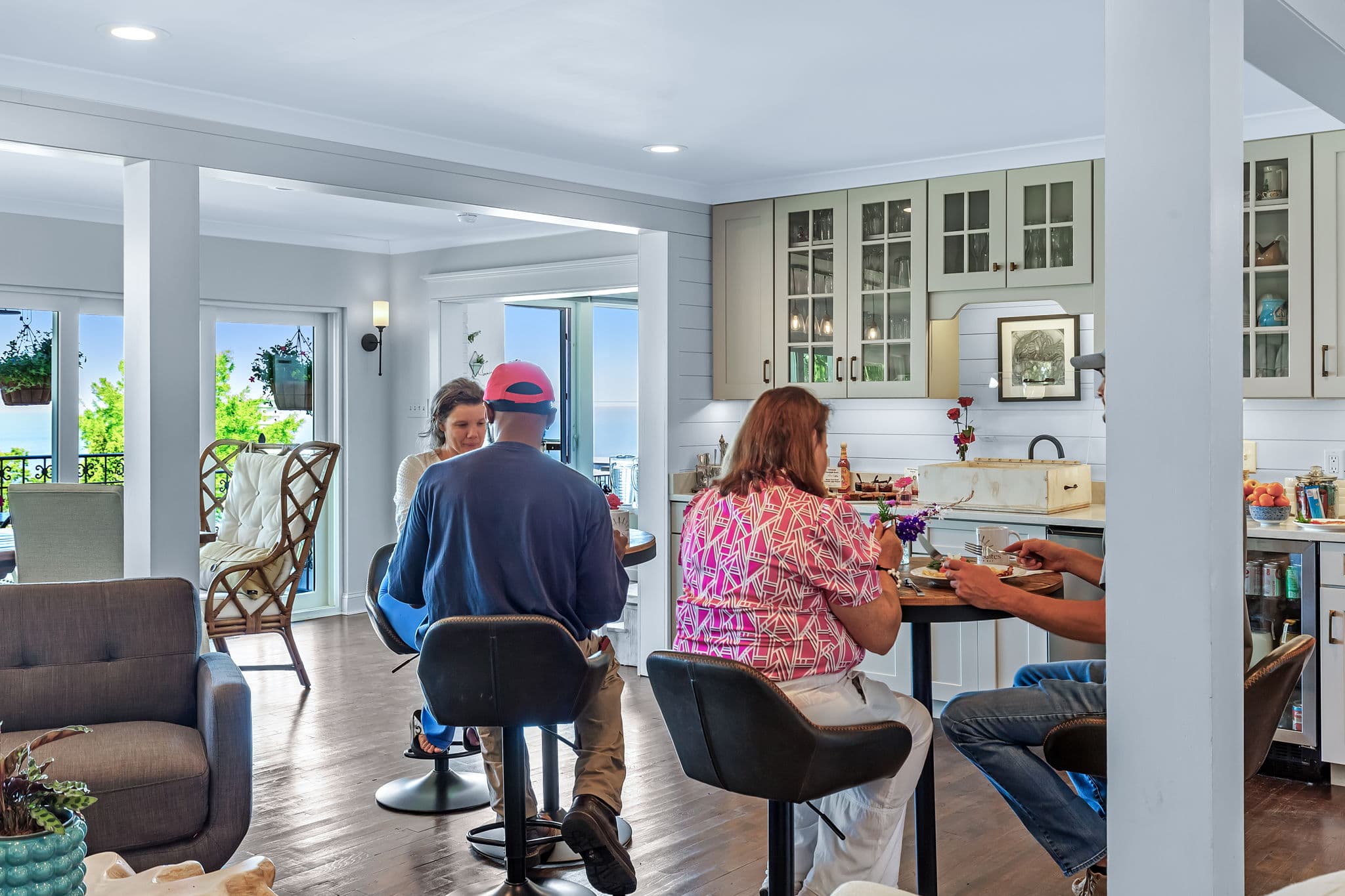 A group of people sitting at tables for two enjoying breakfast in a spacious living and dining room