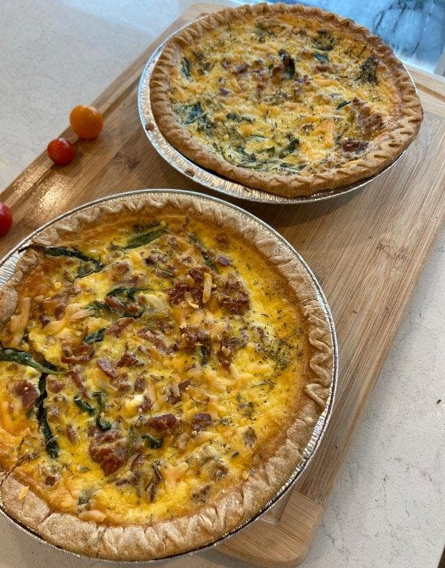 Two baked quiches with a golden crust, filled with spinach, mushrooms, and cheese."