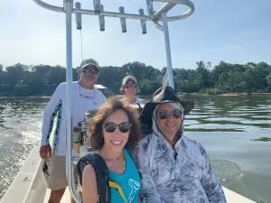 A group of four people is posing on a fishing boat on a sunny day.