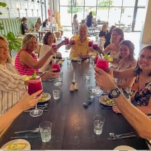 A group of people at a restaurant raising drinks in a celebratory toast around a table.