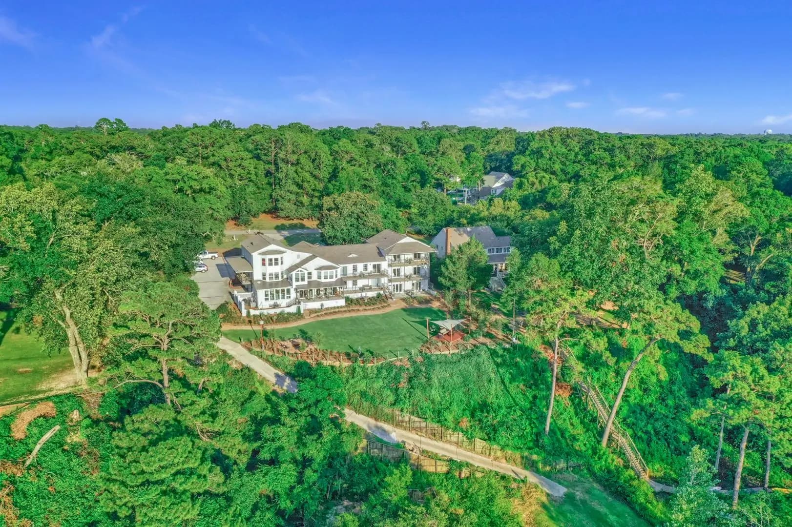 Aerial view of a modern house surrounded by dense greenery.