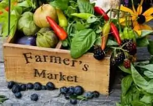 A wooden crate labeled "Farmer's Market" filled with various colorful fruits and vegetables.
