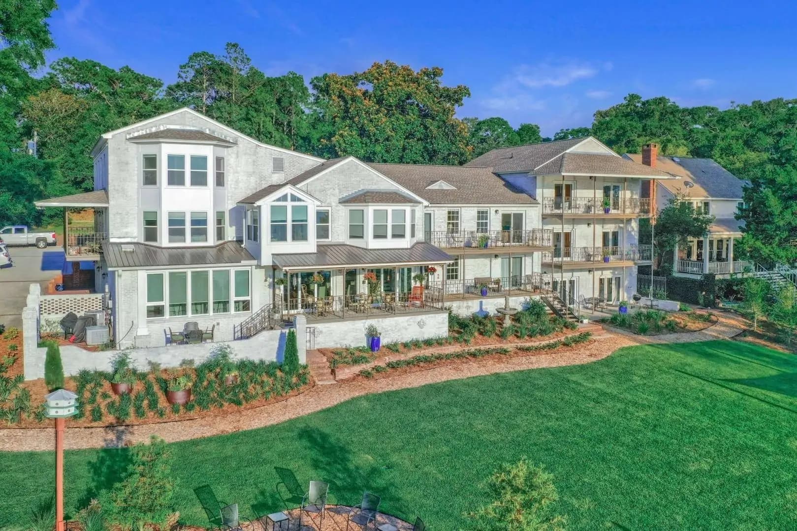 A spacious, multi-level home surrounded by lush greenery and landscaped gardens.