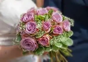 A close-up of a bouquet featuring pink roses and greenery.