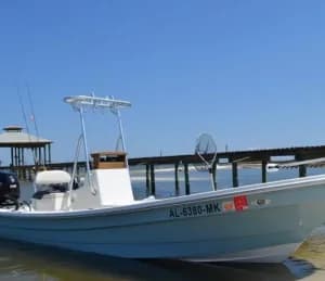A light blue motorboat is moored at a dock on a clear day.