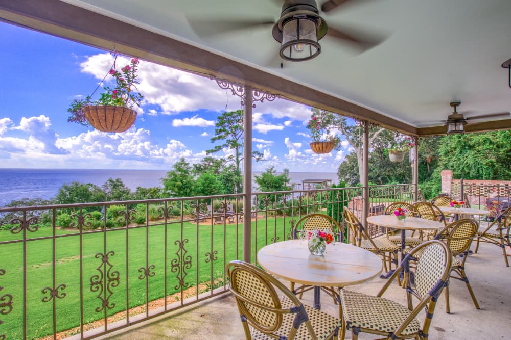 A cozy outdoor seating area with tables and chairs overlooking a lush landscape and water.