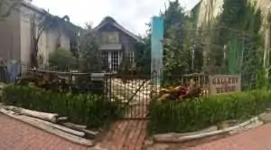 A cozy garden with a gated entrance and a quaint building in the background.