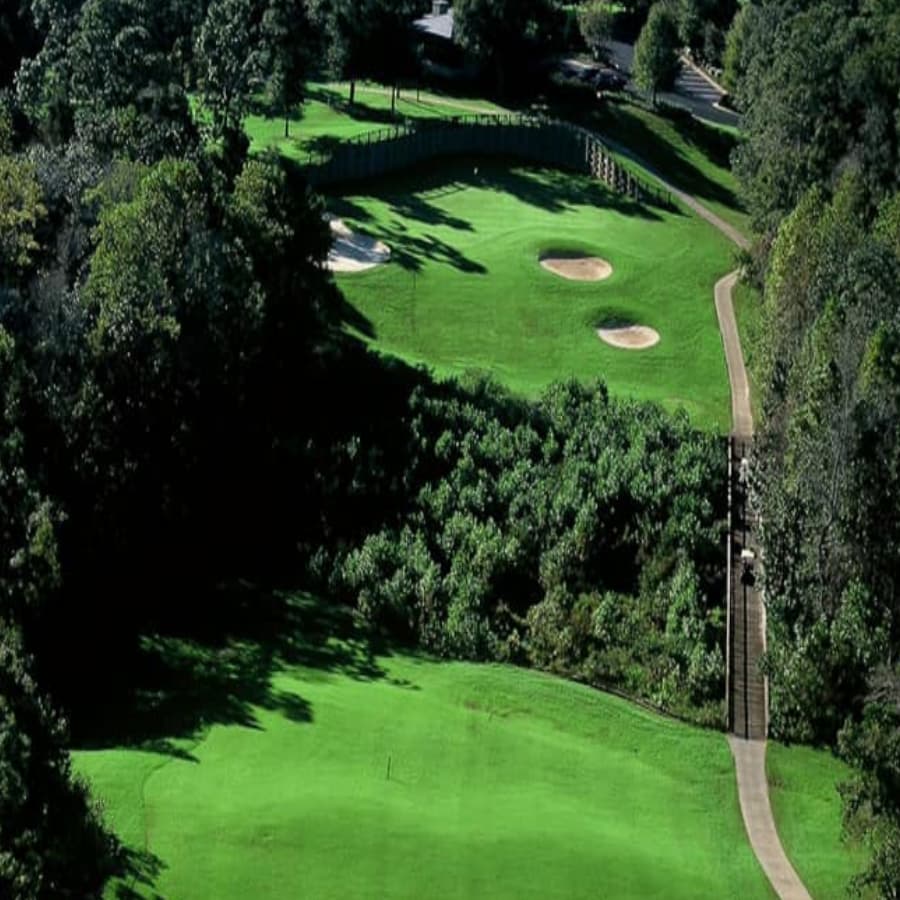 An expansive golf course with green, sand pits, flags and trees.